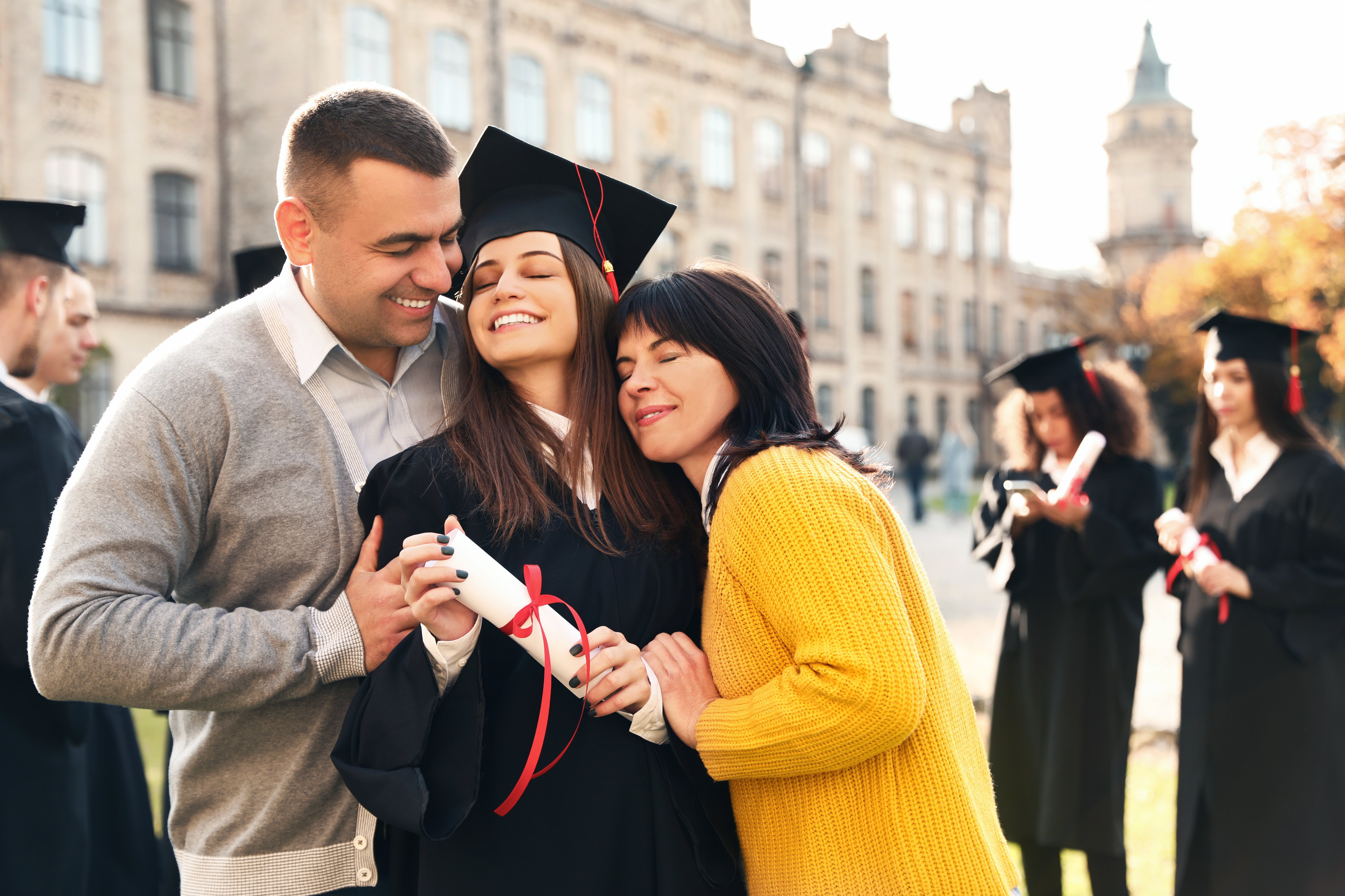 Two parents hugging their daughter on her graduation day