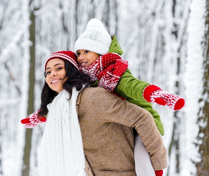 A mother and daughter outside in the snow.